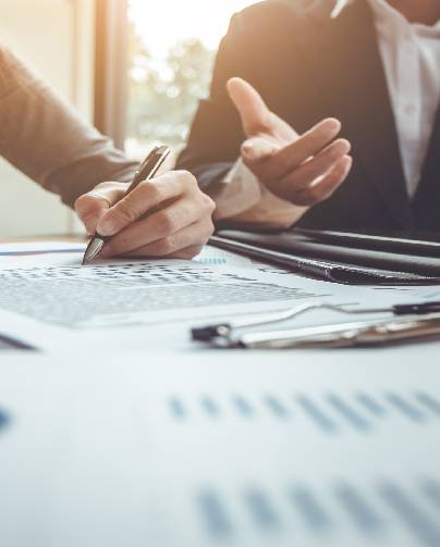 Two people analyzing financial charts and data with pens and documents.