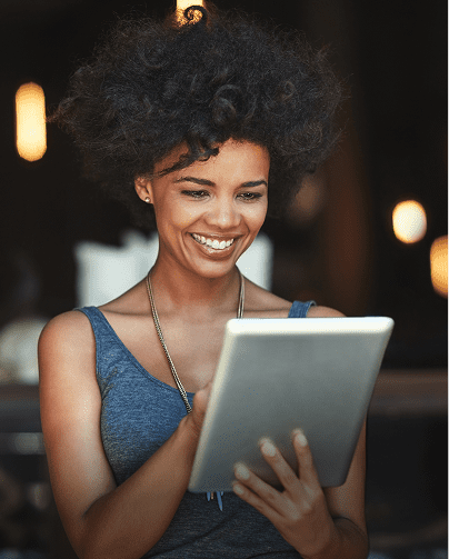 Smiling woman using a tablet in a cozy setting.