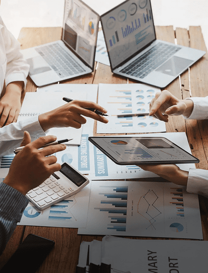 Team analyzing financial data with laptops, tablet, and calculator.