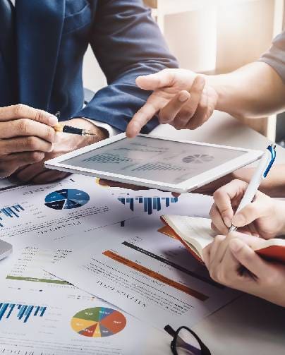 People analyzing financial charts and data on paper and a tablet.