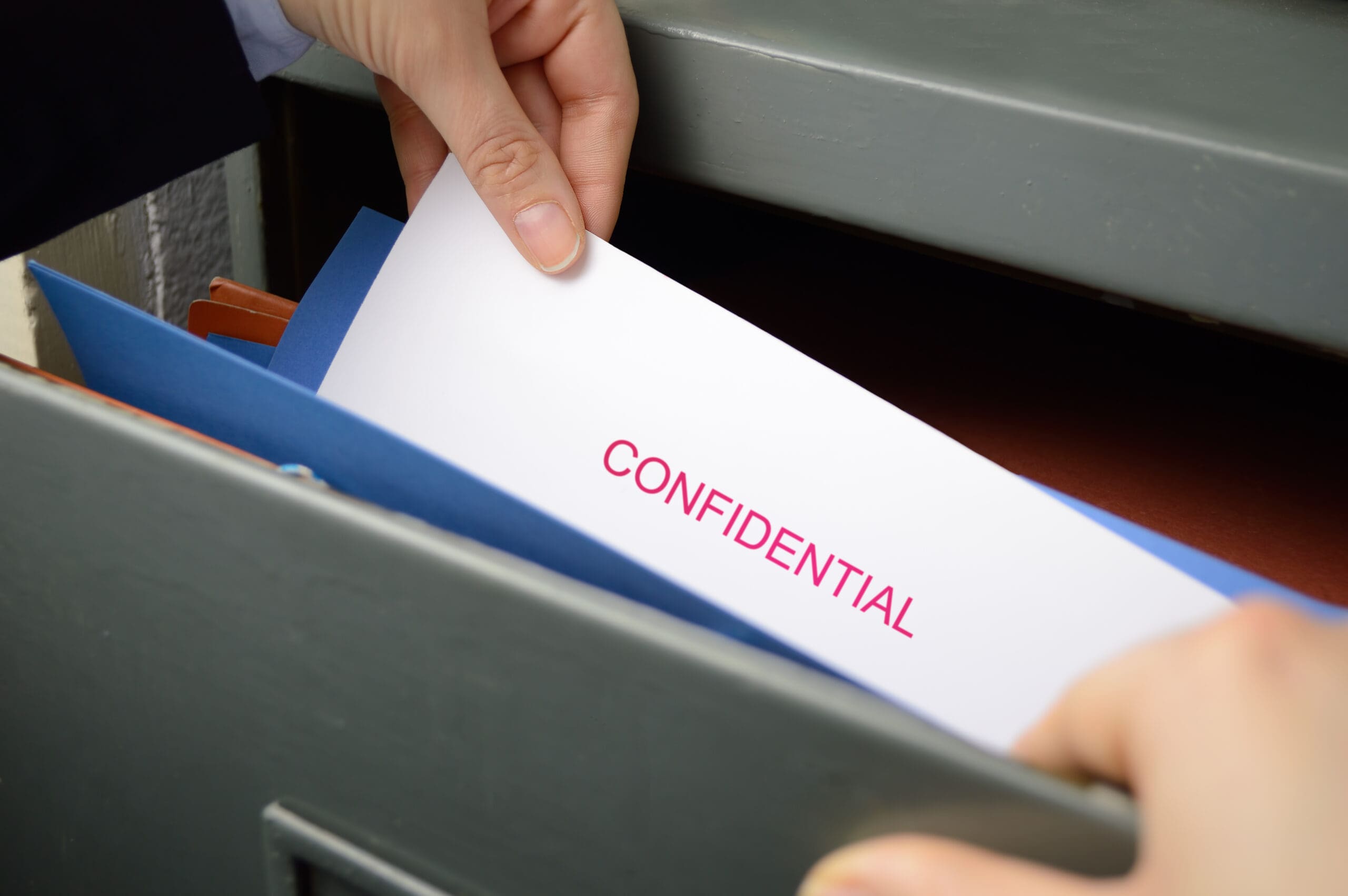 Person placing a confidential document into a filing cabinet.